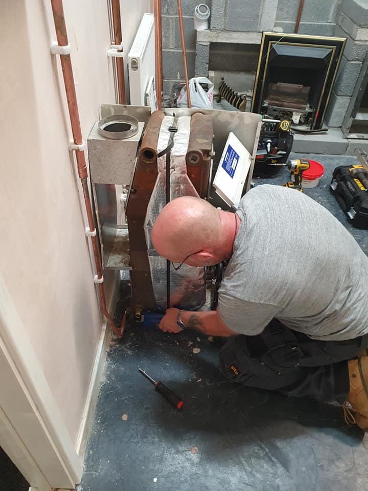 Gas engineer repairing boiler in training centre in Swansea