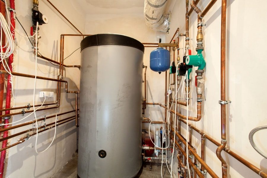Grey unvented hot water system installed in boiler room with pipework